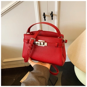 Close-up of red lychee pattern leather handbag with gold metal lock and handle detail