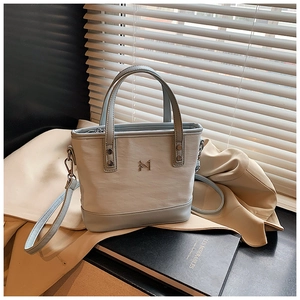 Close-up of white and light blue bucket bag with metal M logo and adjustable strap