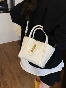 Chic white crocodile embossed bucket bag with gold clasp shown on a model