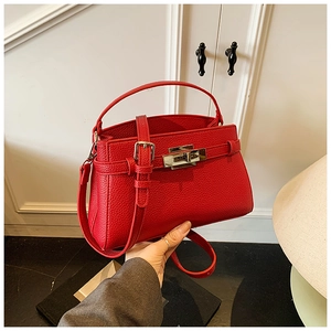 Detailed view of red lychee pattern leather handbag with silver metal buckle and strap