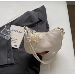 Dettaglio della borsa a spalla bianca con cuore di perle e fiocco in pizzo raffinato