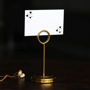 Close-up of golden heart place card holder with thick round base for wedding tables