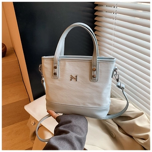 Detail of light blue and beige canvas bucket bag with adjustable shoulder strap