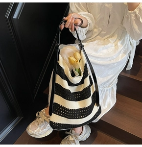 Close-up of black and white woven tote bag texture with leather shoulder strap details