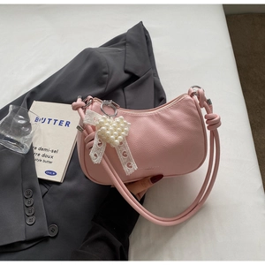 Dettaglio borsa a mezzaluna rosa in pelle a grana fine con ciondolo a cuore perlato