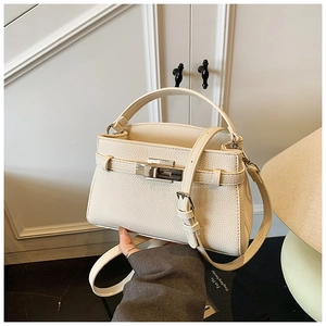 Detail of creamy white litchi grain leather texture and silver buckle on Kelly handbag