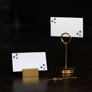 Close-up of golden metal heart-shaped card holders and decorative cards on wood