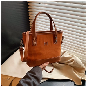 Close-up of orange canvas bucket bag with brown leather trim and metallic N logo