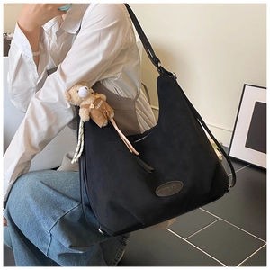 Detail of black oversized hobo bag featuring soft texture and a cute bear charm
