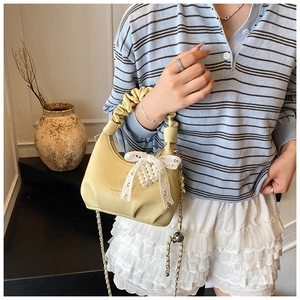 Detail of light yellow crescent bag with lace bow, pearl beads and pleated handle