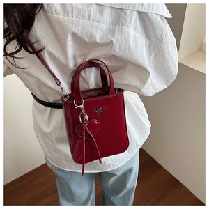 Detail of red patent leather mini crossbody bag with metal letters and heart charm