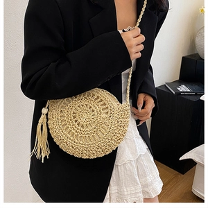 Dettaglio di borsa rotonda in paglia intrecciata con trama radiale e nappa elegante
