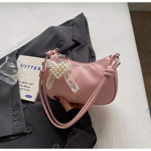 Dettaglio borsa rosa in pelle con ciondolo a cuore di perle e fiocco di pizzo