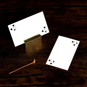 Detail of gold metal holder with laser-cut heart pattern place cards on wood