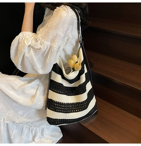 Detail of black and white woven tote bag featuring hollow knit texture and leather strap