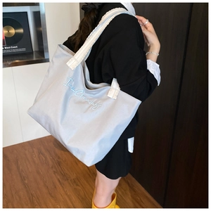 Detail view of a large tote bag with 'I am Creamy' embroidery and durable woven straps