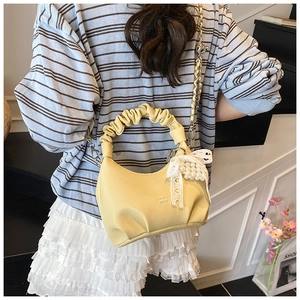 Detail of yellow handbag featuring a ruched handle with lace bow and pearl charm