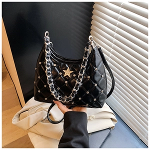 Detailed close-up of black quilted shoulder bag with silver studs and star metal piece