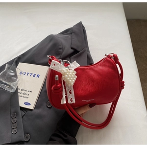 Dettaglio borsa rossa in pelle martellata con ciondolo a cuore di perle e pizzo