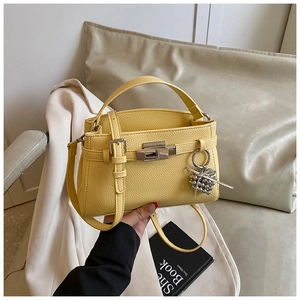 Detail view of yellow litchi pattern leather Kelly bag with silver grape bead charm