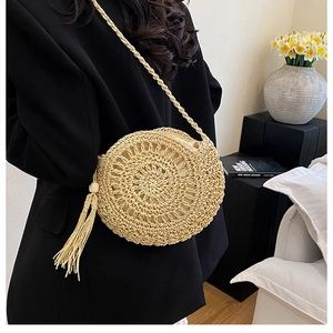 Dettaglio della borsa rotonda in paglia intrecciata con lunghe nappe e tracolla fine