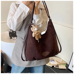 Close-up of brown suede tote bag featuring a cute teddy bear charm and side leather detail