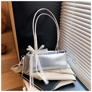 Detail of silver metallic handbag with large white lace bow and round top handles