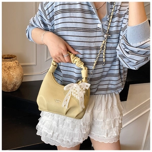 Detail of light yellow leather handbag with lace pearl bow charm and chain strap