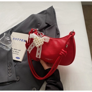 Dettaglio della borsa a mezzaluna in pelle rossa con fiocco e ciondolo di perle