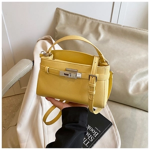 Detail of yellow lychee grain leather handbag with silver lock and adjustable strap