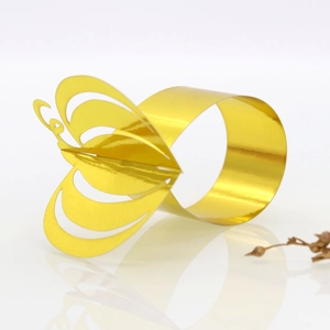 Macro shot of gold butterfly napkin ring with reflective metallic finish and paper texture