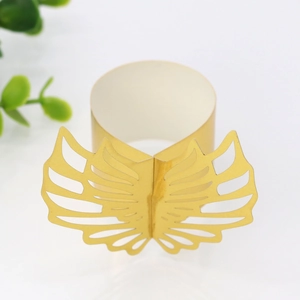 Macro shot of gold laser-cut paper napkin rings with elegant wing-shaped hollow design