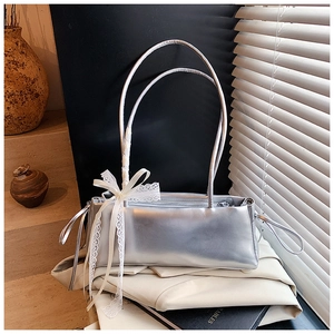 Detail of silver rectangular underarm bag with white lace bow and dual slim straps