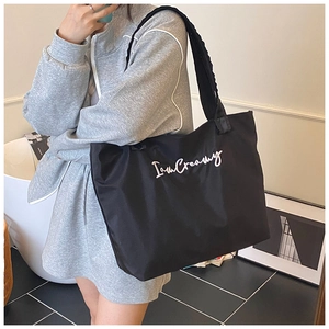 Lifestyle view of a large black nylon tote bag with IamCreamy text on wide shoulder strap