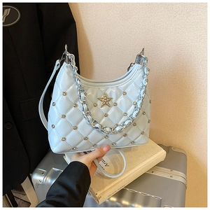 Gros plan du sac matelassé bleu clair avec logo étoile en métal étincelant et chaîne