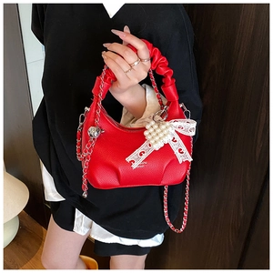 Detail of red hobo bag with litchi leather texture, pearl heart and lace bow charm