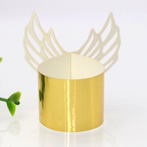 Macro shot of gold paper napkin ring featuring delicate white hollow angel wings for weddings