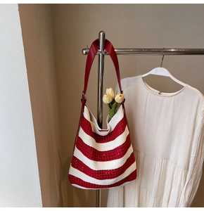 Detail of red and white striped crochet knit tote bag with red leather shoulder strap