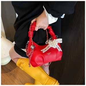 Detail of red lychee grain leather bag with oversized white lace pearl bow charm
