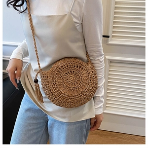 Dettaglio di una borsa a tracolla in paglia intrecciata con nappe laterali e cinturino
