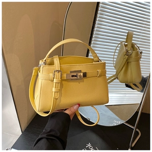 Detail of yellow lychee grain leather handbag with gold metal lock and adjustable strap