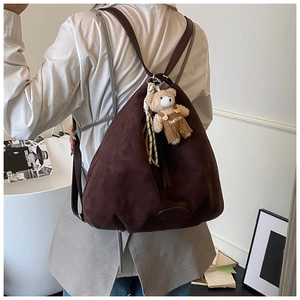 Detail of dark brown suede tote bag with a cute bear charm and striped silk scarf