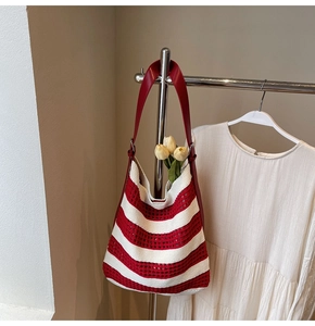 Detail of red and white striped crochet tote bag with red leather handle and floral decor