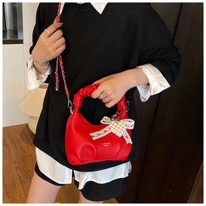 Detail of red pleated handbag with pearl bow charm and silver-red chain strap
