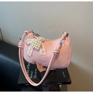 Dettaglio della borsa in pelle litchi rosa con ciondolo a cuore e fiocco in pizzo