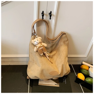 Macro detail of camel suede tote bag with cute teddy bear charm and leather logo