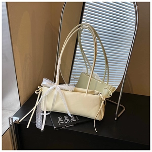 Detailed close-up of cream leather shoulder bag featuring delicate white lace bow accents