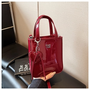 Detail of burgundy patent leather handbag with silver logo and heart charm