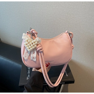 Dettaglio borsa in pelle litchi rosa con ciondoli cuore di perla e fiocco di pizzo