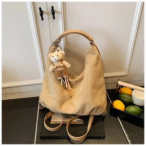 Detail of khaki suede tote bag with teddy bear charm and fashion leather branding